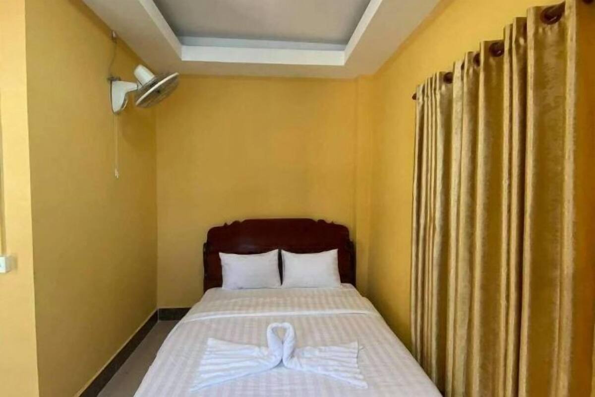 A hotel room with a bed, a ceiling fan, and curtains.