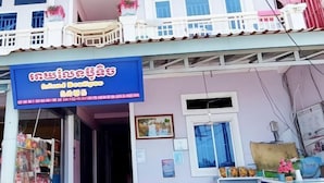 A building with a blue signboard, a red sofa, and a window with a view. - Island Boutique Koh Rong (Sihanoukville)