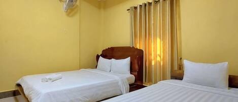 A hotel room with two beds, a ceiling fan, and a window with curtains.