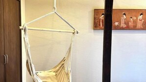 A room with a hanging hammock chair, a wooden wardrobe, and a painting on the wall. - JIA MING (Osaka)