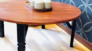 A round wooden table with black legs, a tray with white candles, and a white pitcher on it. - JIA MING (Osaka)