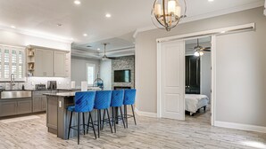 A modern kitchen with a central island, bar stools, and a dining area.