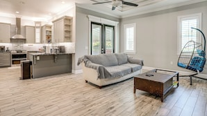 A spacious living area with a sofa, coffee table, and a hanging chair.