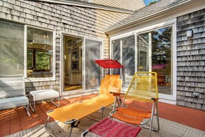 An outdoor patio with a sun lounger, a chair, and a table. - 4,200 Sq Ft Mid-cape Cottage w/ Furnished Deck! (Brewster)