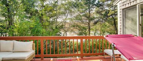 A wooden deck with outdoor furniture, including a sofa, chairs, and a table.