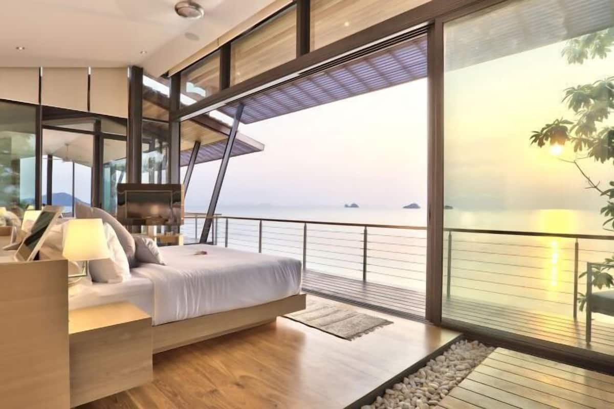 A modern bedroom with a large window overlooking a body of water.