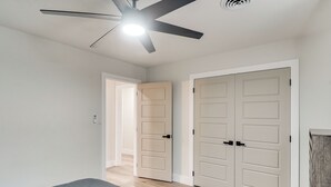 A bedroom with a bed, a ceiling fan, and two doors. - Backyard & Game Room! Home in Heart of Midland (Midland)