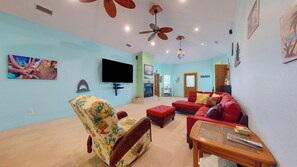 A living room with a television, a fireplace, a sofa, and a ceiling fan.