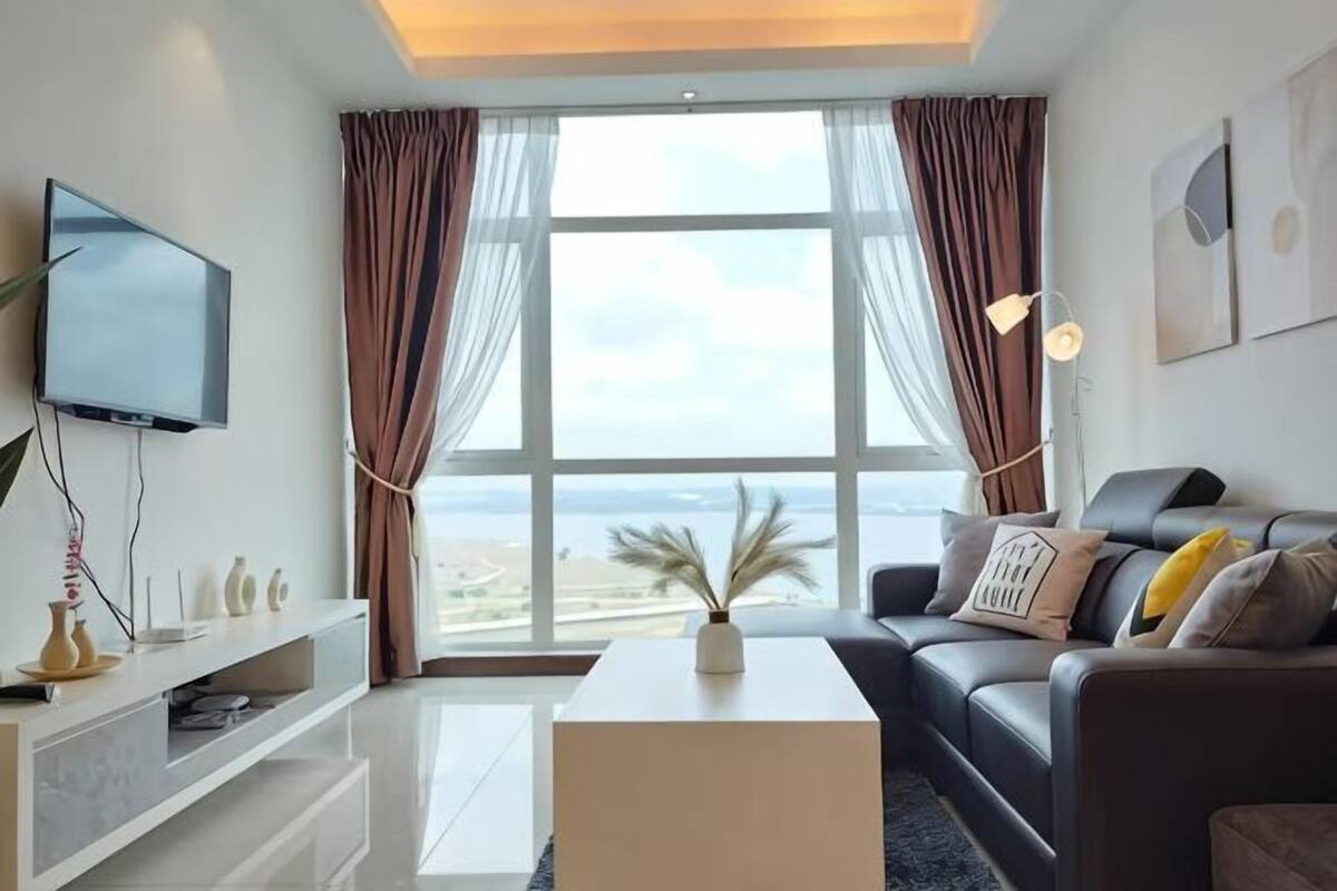 A modern living room with a large window, a flat-screen TV, a sofa, and a coffee table.