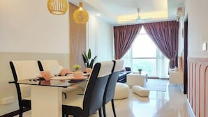 A modern dining area with a glass table, white chairs, and two pendant lights. - Delight Homestay Paragon Residences (Johor Bahru)