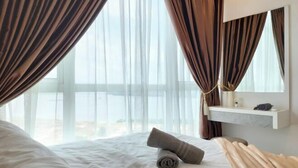 A hotel room with a bed, curtains, a bedside table, and a window with a view. - Delight Homestay Paragon Residences (Johor Bahru)