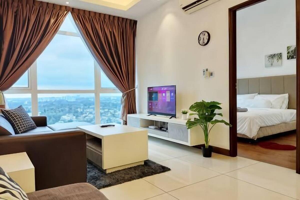 A modern living room with a sofa, a coffee table, a TV, and a potted plant.