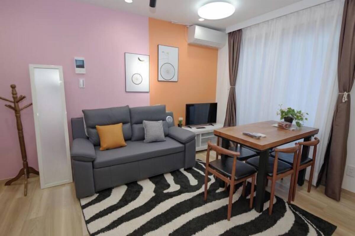 Una sala de estar con sofá, televisión y mesa con sillas.