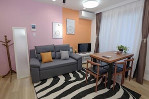 A living room with a sofa, TV, and table with chairs.