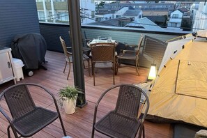 Un balcón con una mesa, sillas, una tienda de campaña y una planta en maceta.