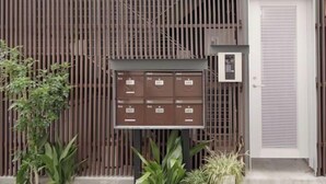 A building facade with a vertical wooden panel design, a mail slot with labels, and a door with a textured panel.