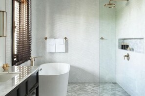 A bathroom with a freestanding bathtub, a vanity with a mirror, and a shower area.