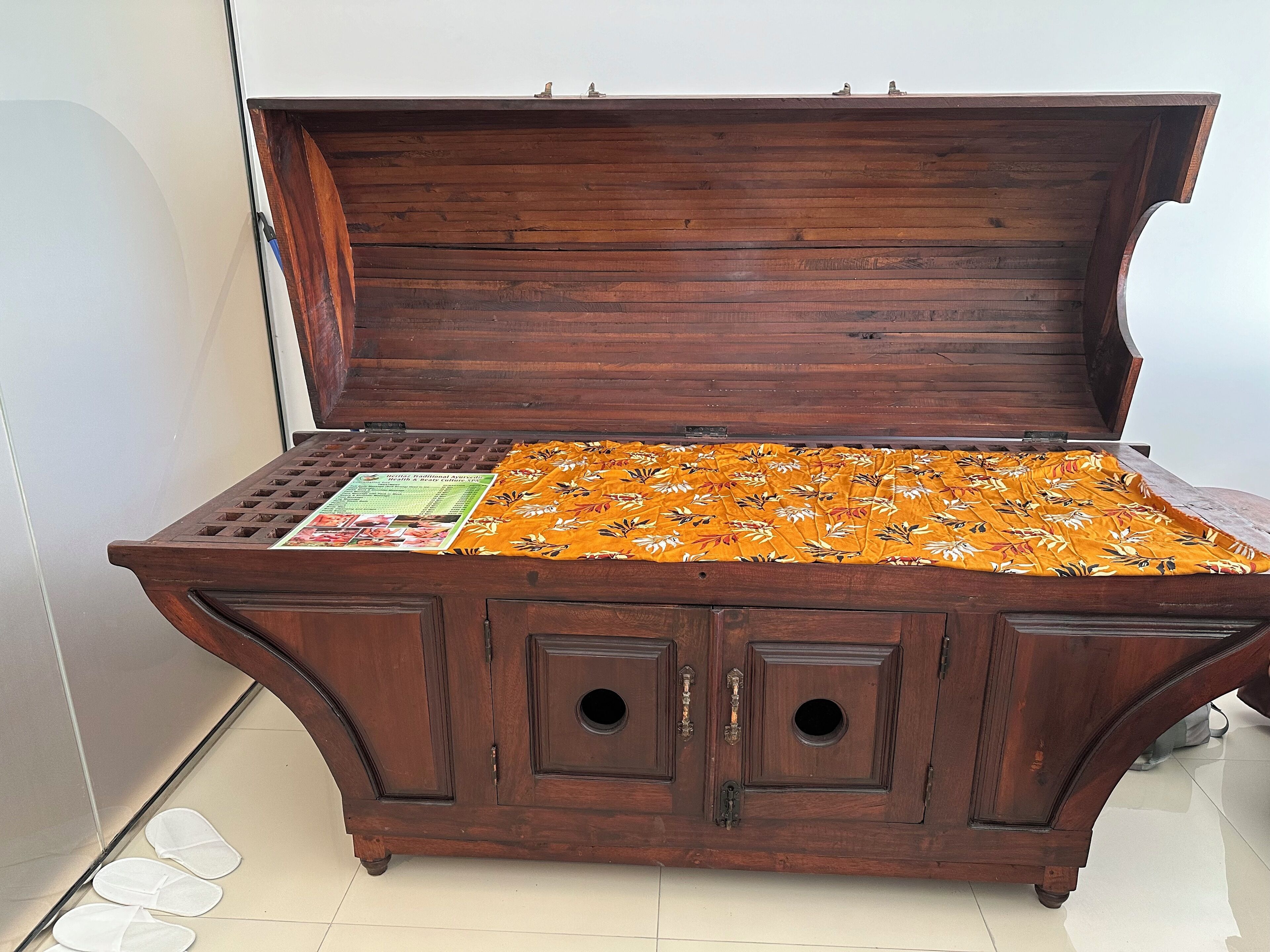 A wooden chest with a hinged lid, a patterned fabric inside, and two small circular cutouts on the front.