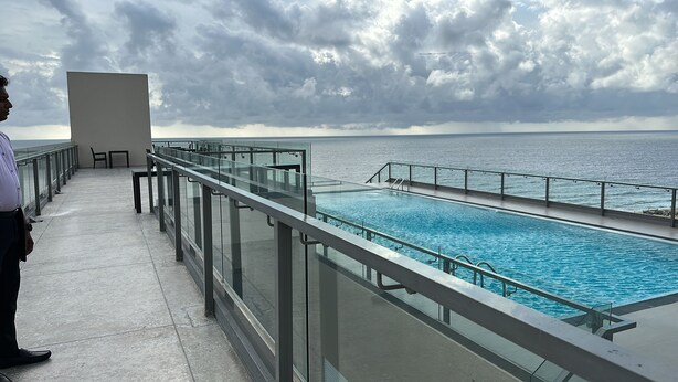 A poolside area with a glass railing overlooking the sea, a seating area, and a clear view of the ocean. - COASTAL COCOON STUDIO NEGOMBO (Negambo)