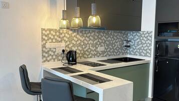 A modern kitchen with a central island, bar stools, pendant lighting, and a built-in oven.