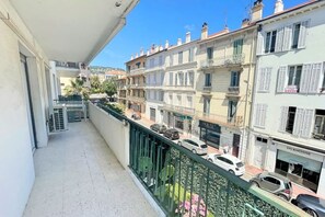 A balcony with a view of adjacent buildings, a street with parked cars, and a clear sky. - Viva Riviera Large 3 Bedrooms with balcony (Cannes)