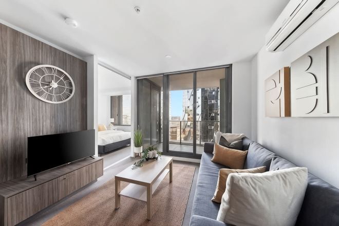A modern living room with a flat-screen TV, a sofa, a coffee table, and a large window.
