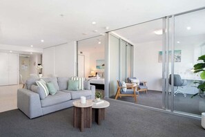 A modern office space with a grey sofa, wooden coffee table, and a glass partition.