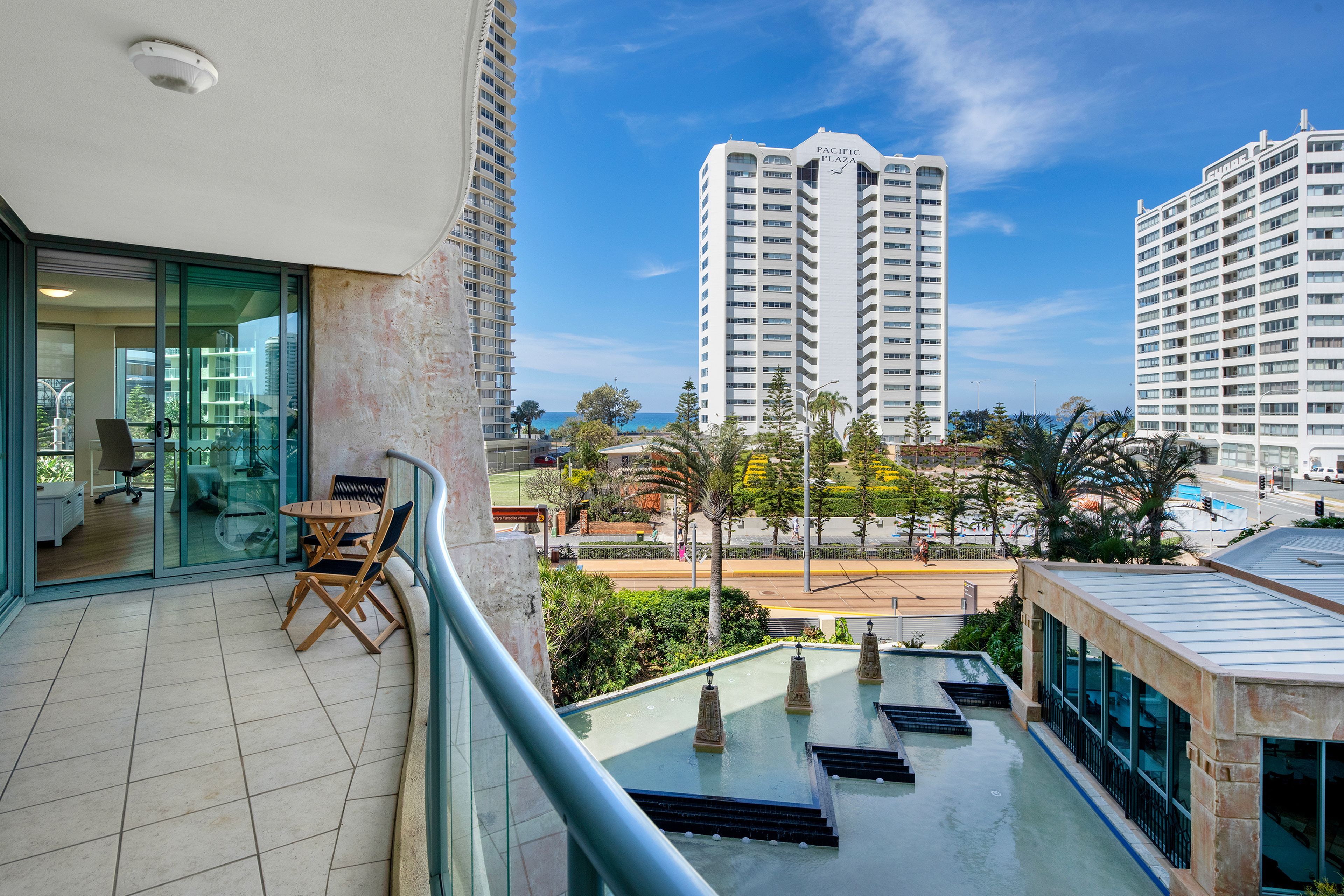 A balcony with a view of a tall building labeled 'Pacific Plaza' and a pool area with steps leading down to the pool.