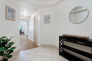 A hallway with a black console table, a round mirror, and framed pictures on the walls. - Family Fun at Sun City 3BR Near Beach (Surfers Paradise)
