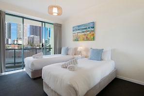 A hotel room with two beds, a city view, a painting, and a hanging light fixture. - Family Fun at Sun City 3BR Near Beach (Surfers Paradise)