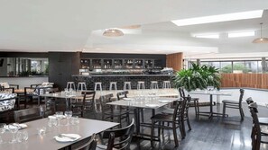 Un restaurant moderne doté d’un bar, de plusieurs tables et de chaises.