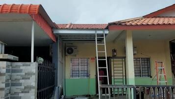 Um edifício residencial com telhado em telhas, varanda coberta e escada.