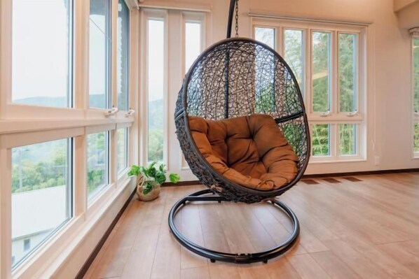 A room with large windows, a hanging chair, and a potted plant. - Villa Atami (Atami)
