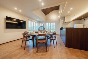 A modern kitchen with a dining area, large windows, and a flat-screen TV mounted on the wall. - Villa Atami (Atami)