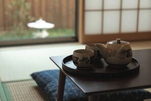 A traditional Japanese tea set on a tray, a window with a view of a garden, and a wooden floor.