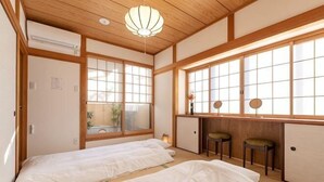 A traditional Japanese-style room with tatami flooring, two beds, a desk, and a window with a view. - KIRAKU･RAKUTEI (Kyoto)
