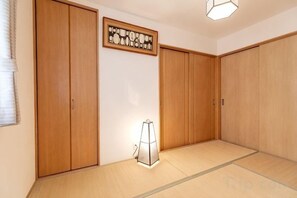 A room with wooden sliding doors, tatami flooring, and a wall-mounted light fixture. - KIRAKU･RAKUTEI (Kyoto)