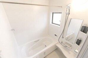 A modern bathroom with a bathtub, a shower, a window, and a mirror. - KIRAKU･RAKUTEI (Kyoto)