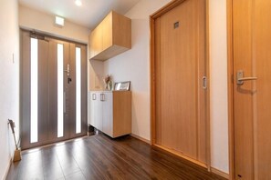 A hallway with wooden flooring, a wooden door, and a cabinet with a vase. - KIRAKU･RAKUTEI (Kyoto)