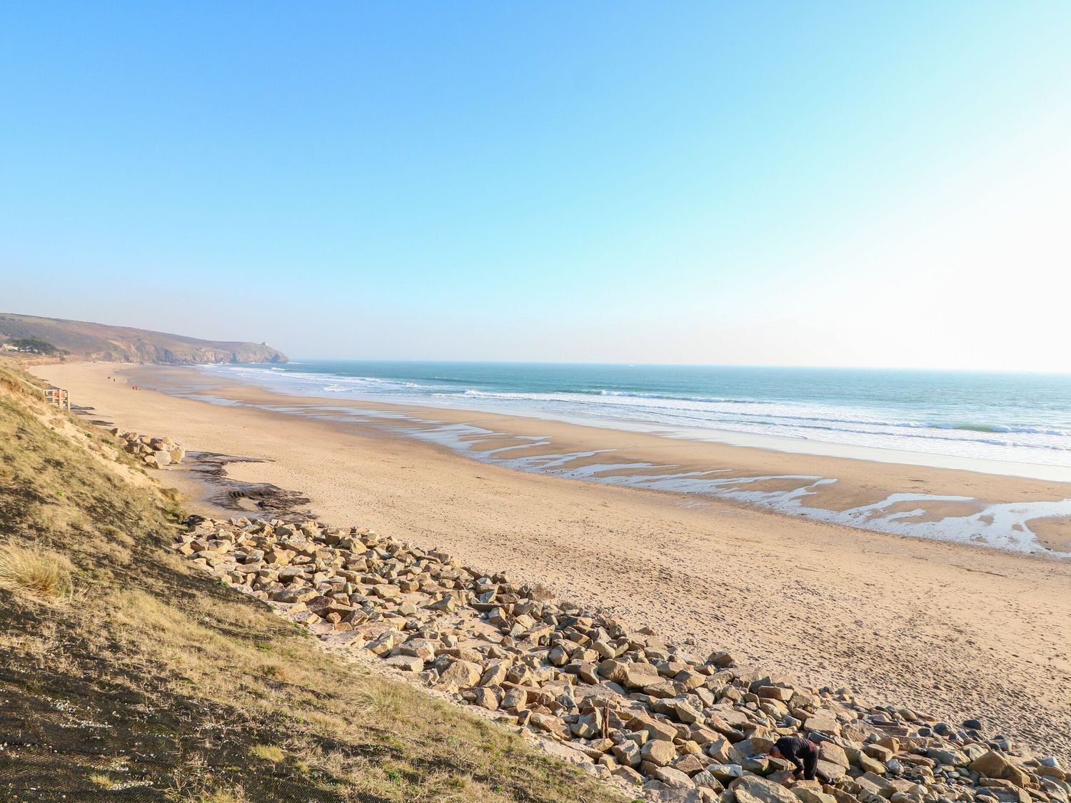A coastal beach with rocky terrain and a clear view of the ocean.