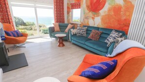 Una sala moderna con un sofá color turquesa, un sillón naranja y una mesa de centro blanca.