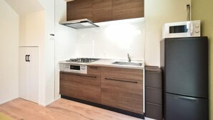 A compact kitchen with a gas stove, a microwave, and a refrigerator. - Hana House Tokyo - Private House (Tokyo)