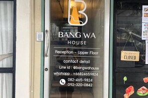 A hotel entrance with a reception sign on the upper floor, contact details, and a closed sign on the door. - Bangwa House - MRT Bangwa Station (Bangkok)