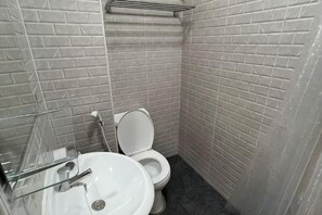 A bathroom with a white toilet, a sink, and a mirror. - Bangwa House - MRT Bangwa Station (Bangkok)