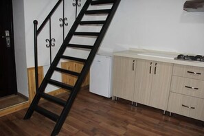 Une cuisine avec un plancher en bois, un réfrigérateur blanc et des armoires en bois.