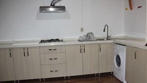 A kitchen with wooden cabinets, a gas stove, a sink, and a washing machine.