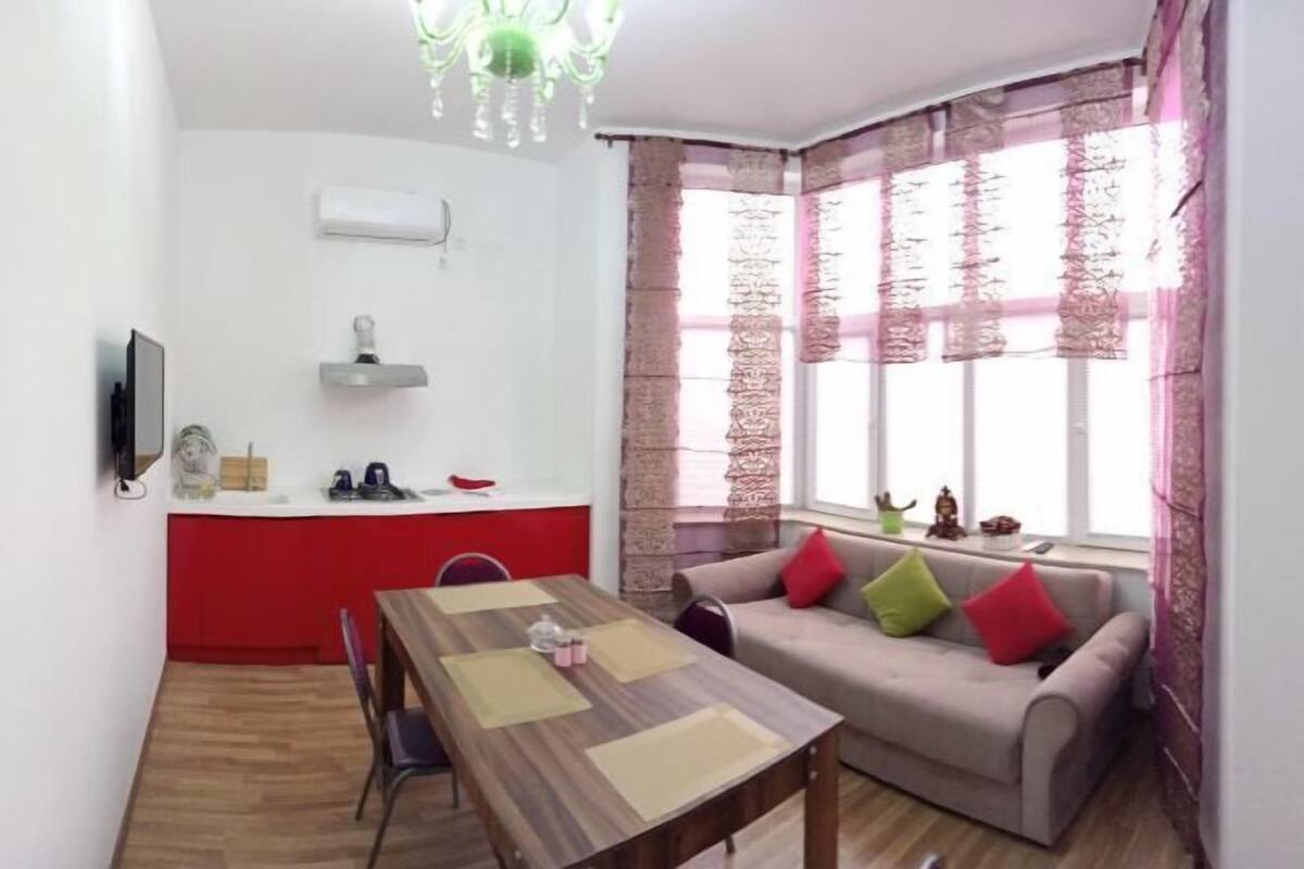 A compact living space with a dining table, sofa, and a TV mounted on the wall.
