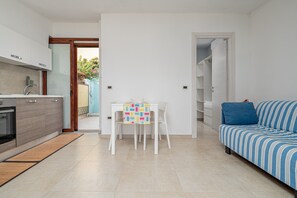 Une cuisine moderne avec des meubles blancs, une table à manger avec des chaises et un canapé à rayures.