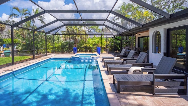A covered outdoor swimming pool with lounge chairs and a patio area.