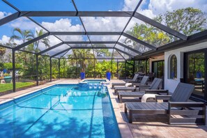A covered outdoor swimming pool with lounge chairs and a patio area. - Chic Siesta Retreat w/ Golf Cart, Pool & Hot Tub! (Siesta Key)
